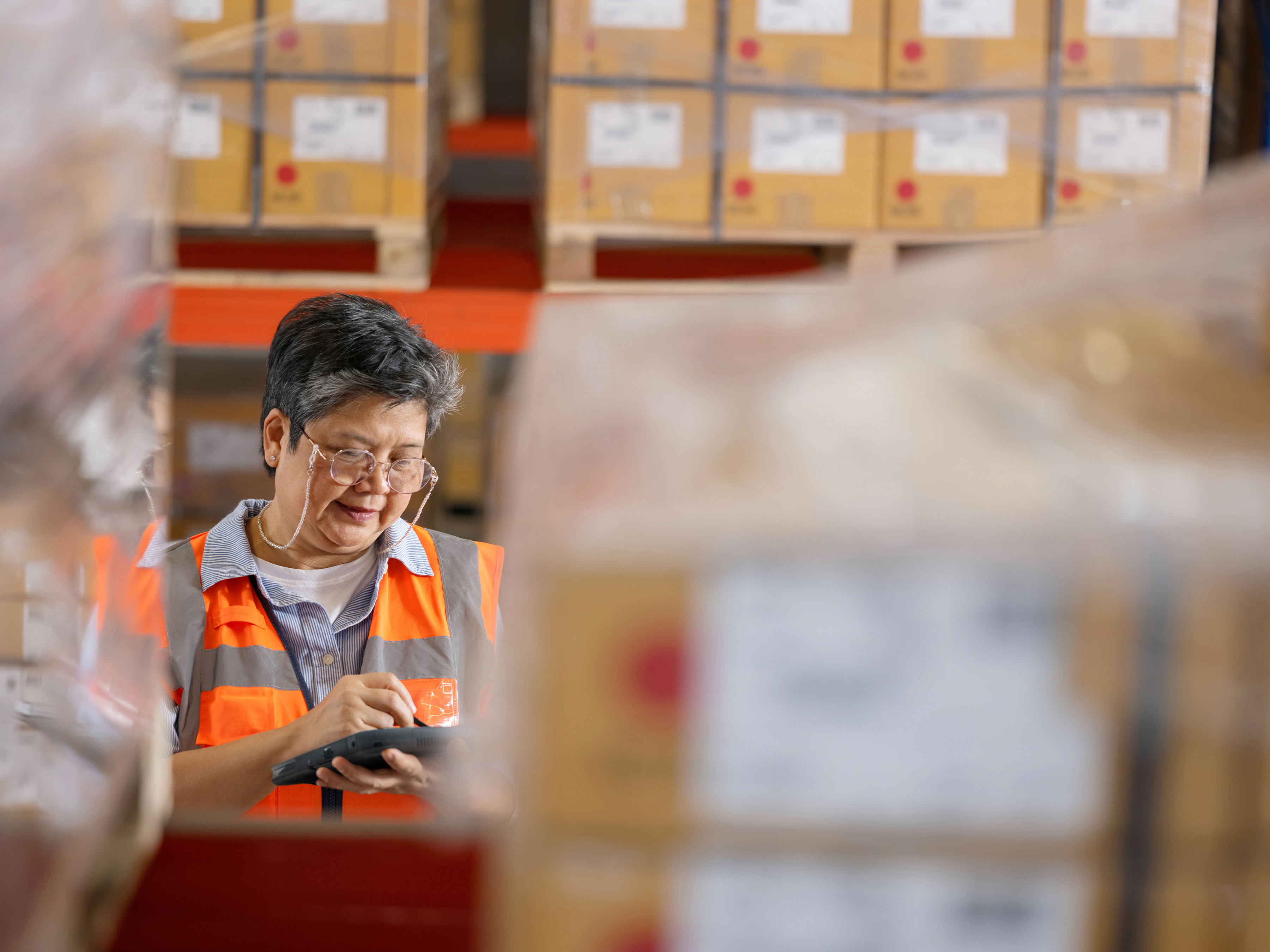 An employee checking a pallet with a tablet inside of a warehouse. An employee checking a pallet with a tablet inside of a warehouse.
