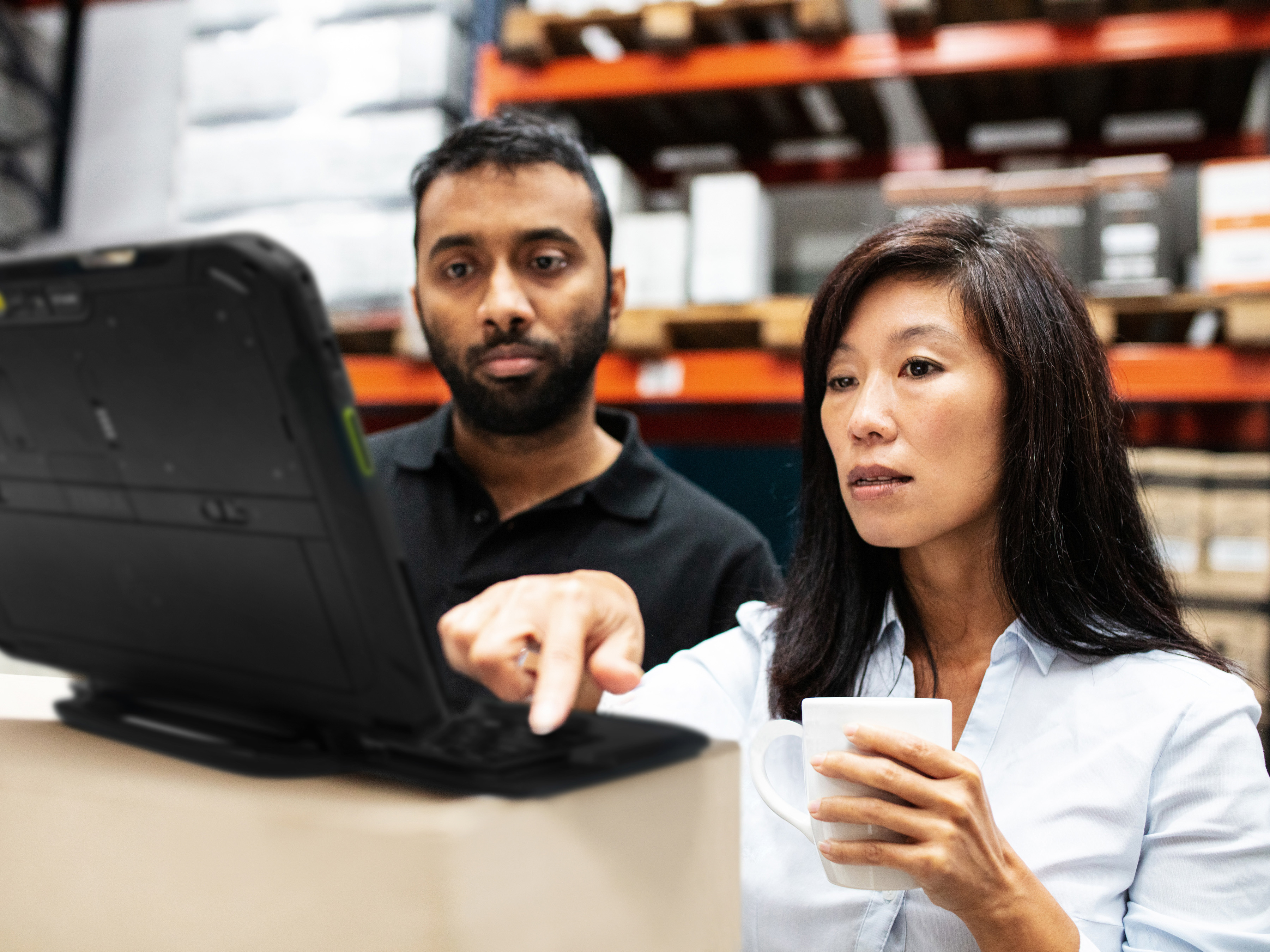 Employees reviewing a Zebra tablet in a warehouse. Employees reviewing a Zebra tablet in a warehouse.
