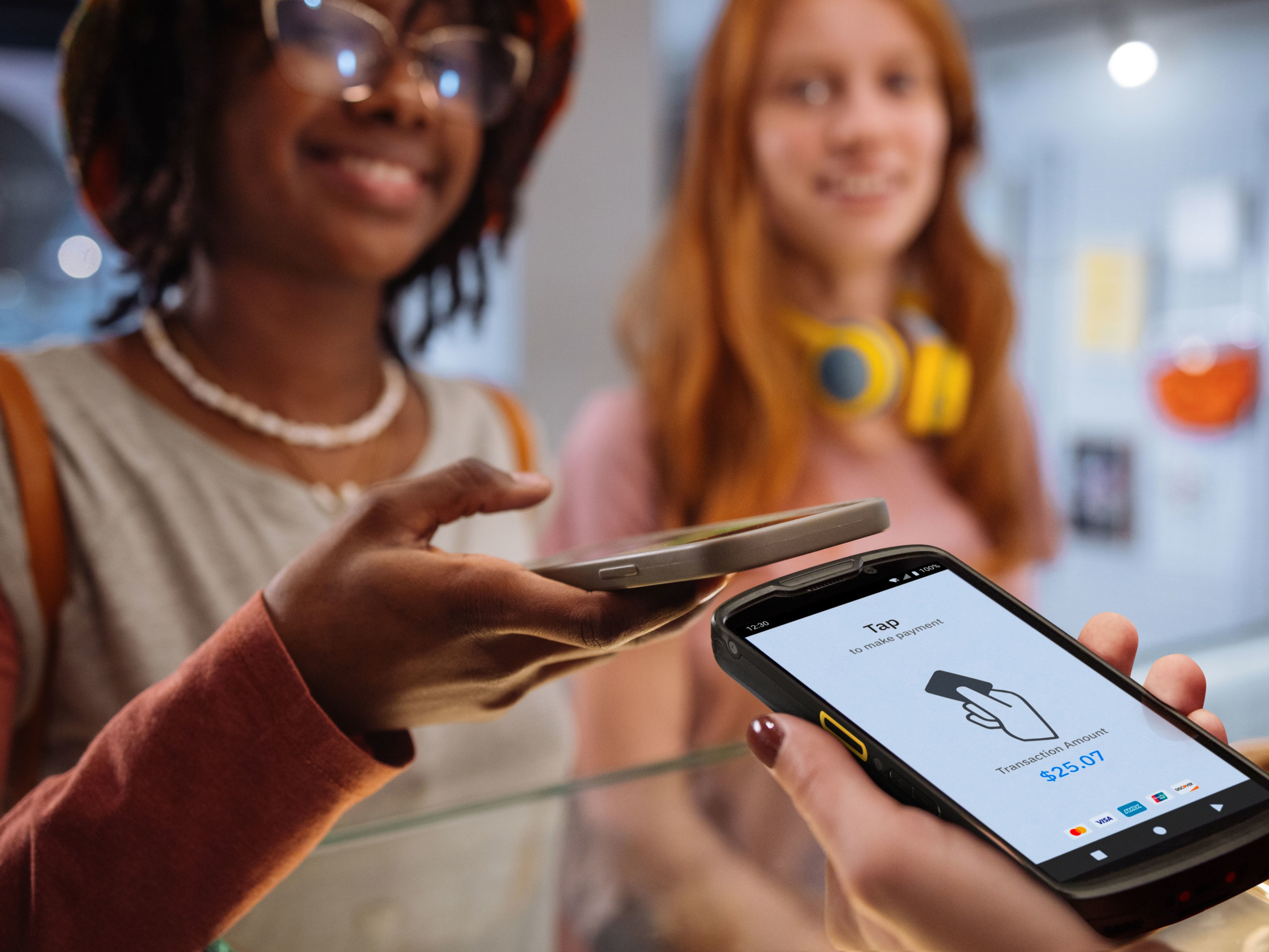 Two people using tap-to-pay to checkout at a cafe. Two people using tap-to-pay to checkout at a cafe.