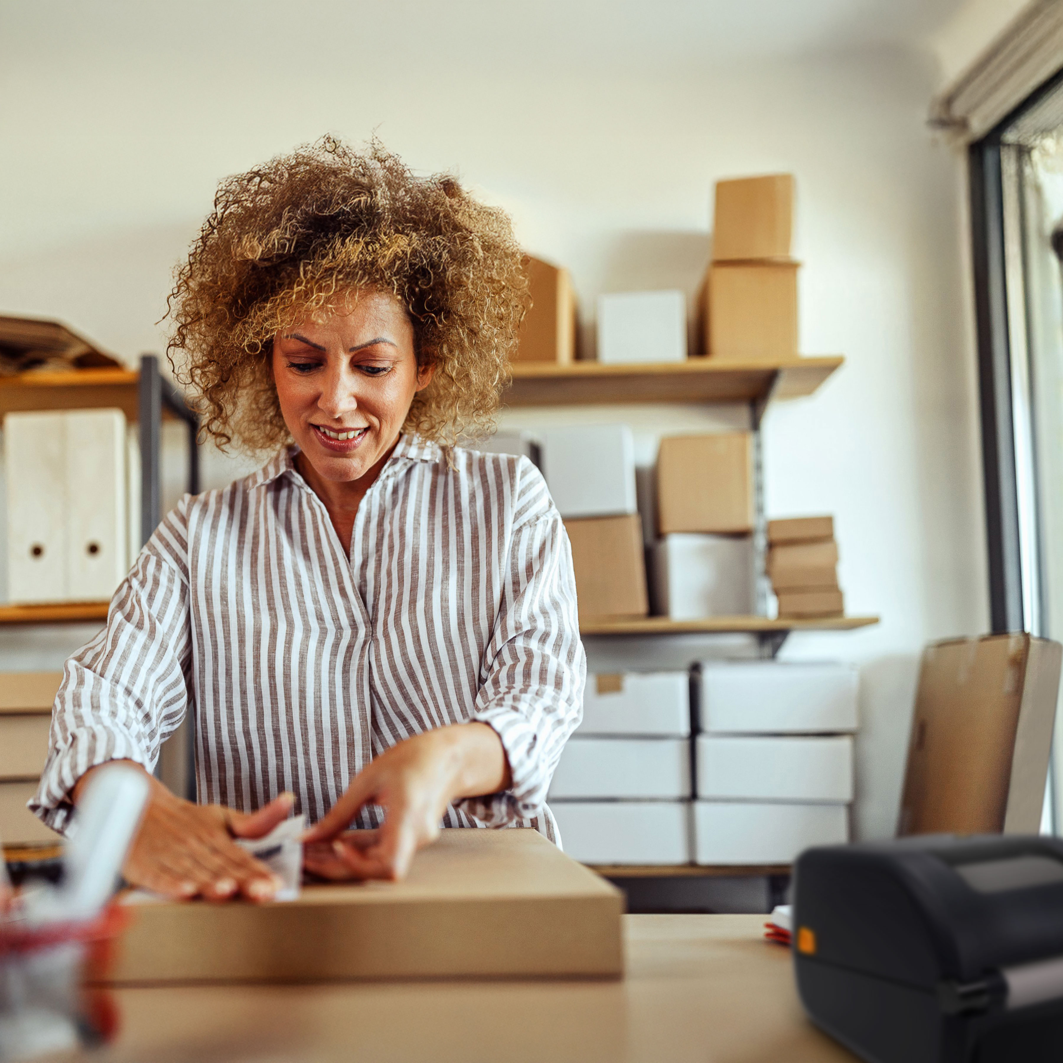 Worker applying a barcode label to a box printed by a Zebra desk Worker applying a barcode label to a box printed by a Zebra desktop printer.