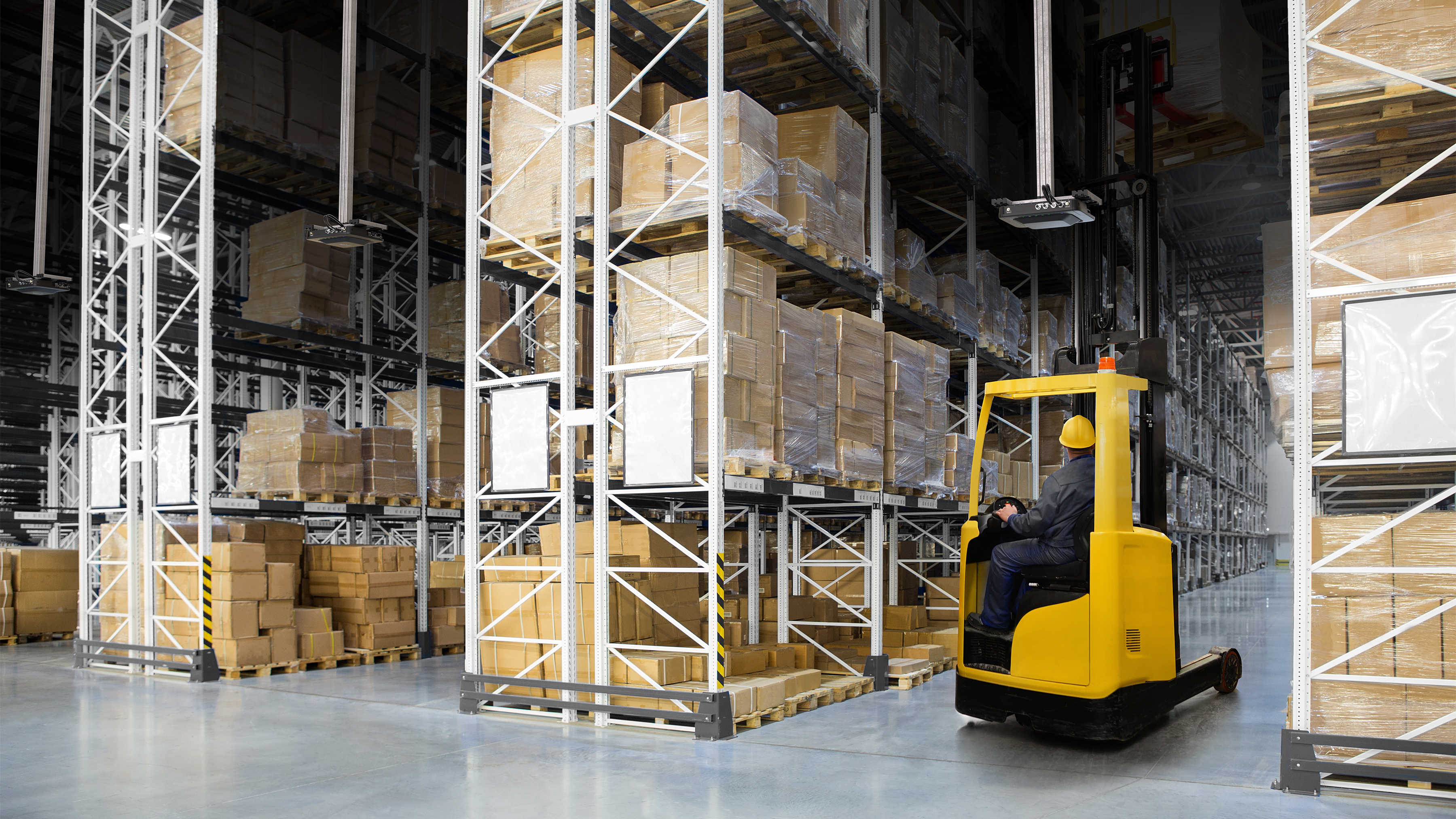 FXR90 Photgraphy Website Warehouse RFID Aisles Closeup 16x9 Worker on a small yellow forklift in a warehouse using the overhead Zebra FXR90 RFID reader to scan multiple barcodes at once in the aisle on many boxes.