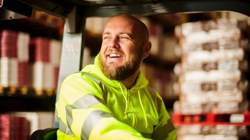Smiling employee driving a forklift in a warehouse. Smiling employee driving a forklift in a warehouse.